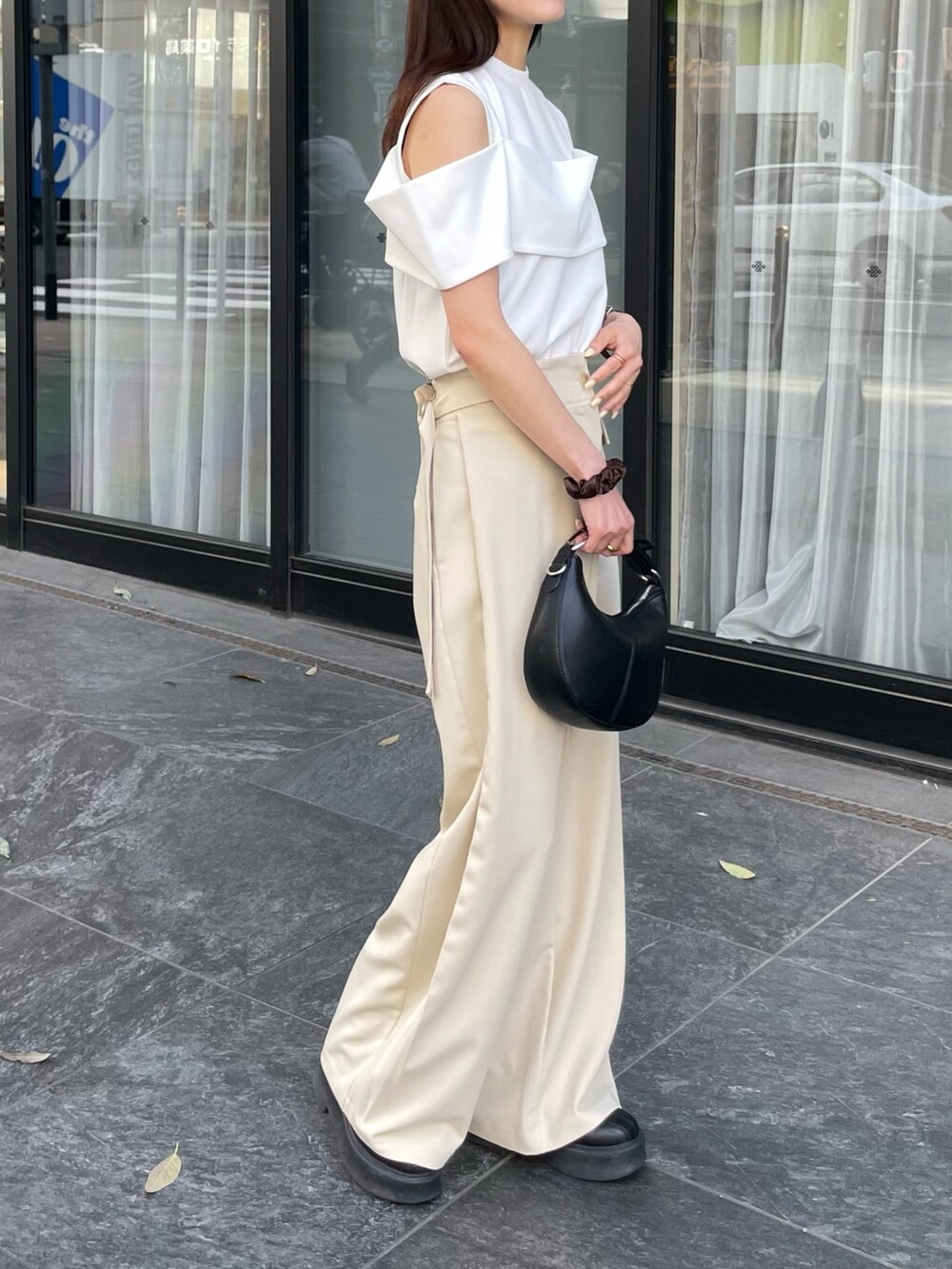 ホワイト系のTシャツ/カットソー、ブラック系のショルダーバッグ、ベージュ系のスラックスを着用したレディースの春コーディネートの2枚目の写真