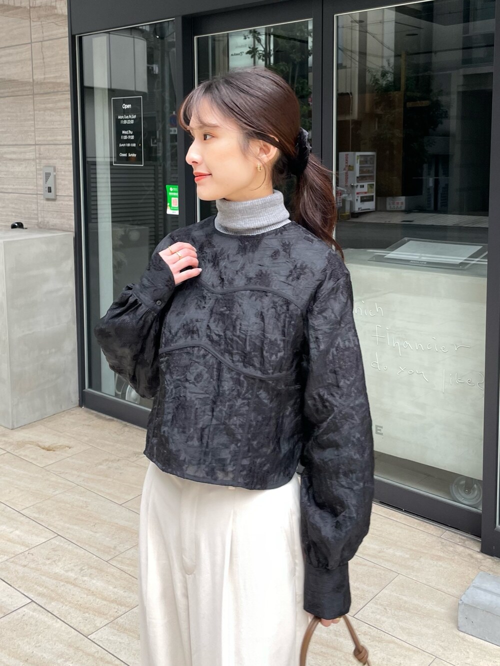 ブラック系のシャツ/ブラウス、ホワイト系のパンツ、ブラウン系のハンドバッグを着用したレディースの冬コーディネートの3枚目の写真