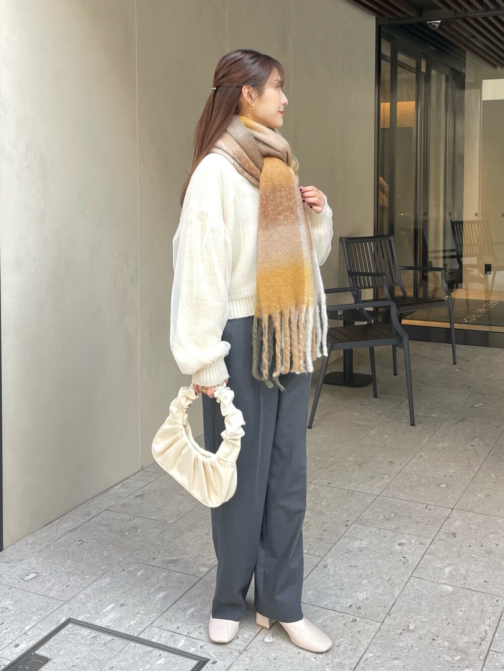 グレー系のパンツ、ホワイト系のニット/セーター、ゴールド系のバレッタ/ヘアクリップを着用したレディースの冬コーディネートの2枚目の写真