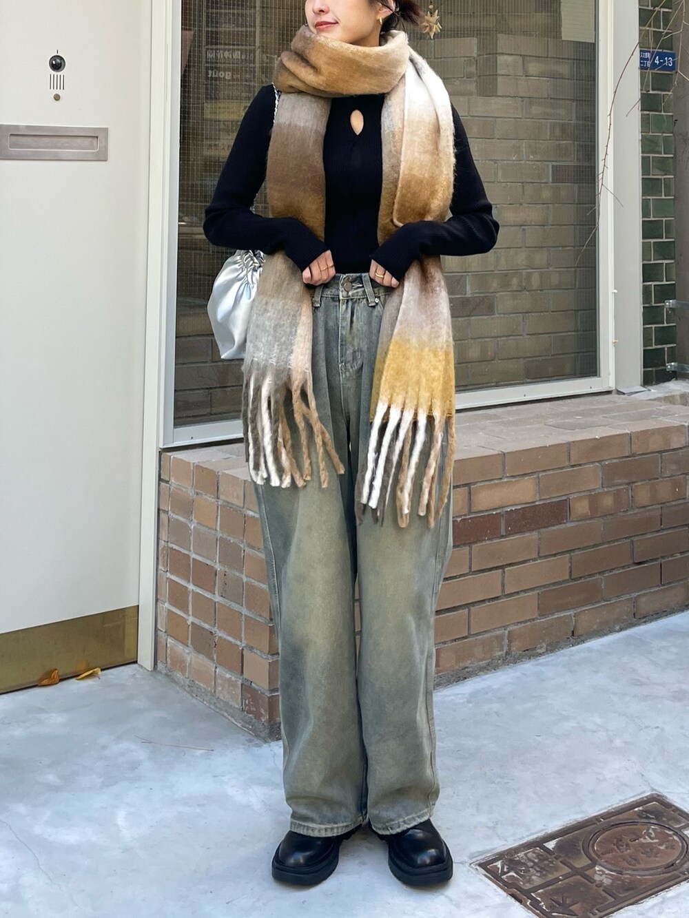 ベージュ系のマフラーを着用したレディースの冬コーディネートの2枚目の写真