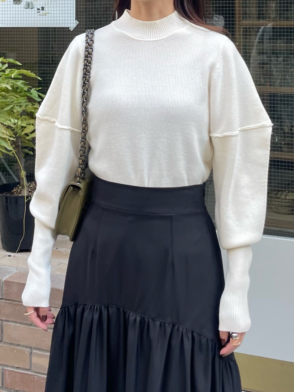 ホワイト系のニット/セーター、ブラック系のスカート、ブラック系のブーツを着用したレディースの秋コーディネートの2枚目の写真