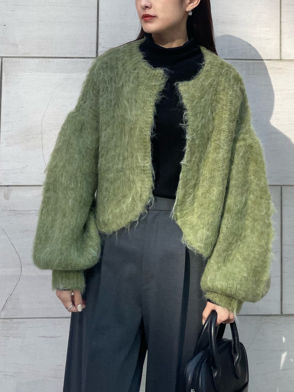 グリーン系のカーディガン/ボレロ、グレー系のパンツ、ブラック系のスニーカーを着用したレディースの秋コーディネートの2枚目の写真