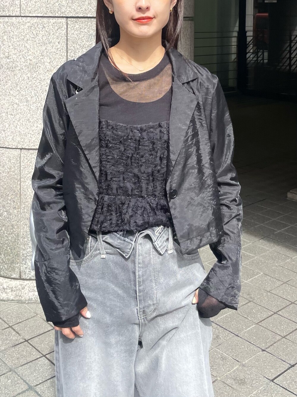 ブラック系のキャミソール、ブラック系のテーラードジャケット、ブラック系のデニムパンツを着用したレディースの春コーディネートの3枚目の写真