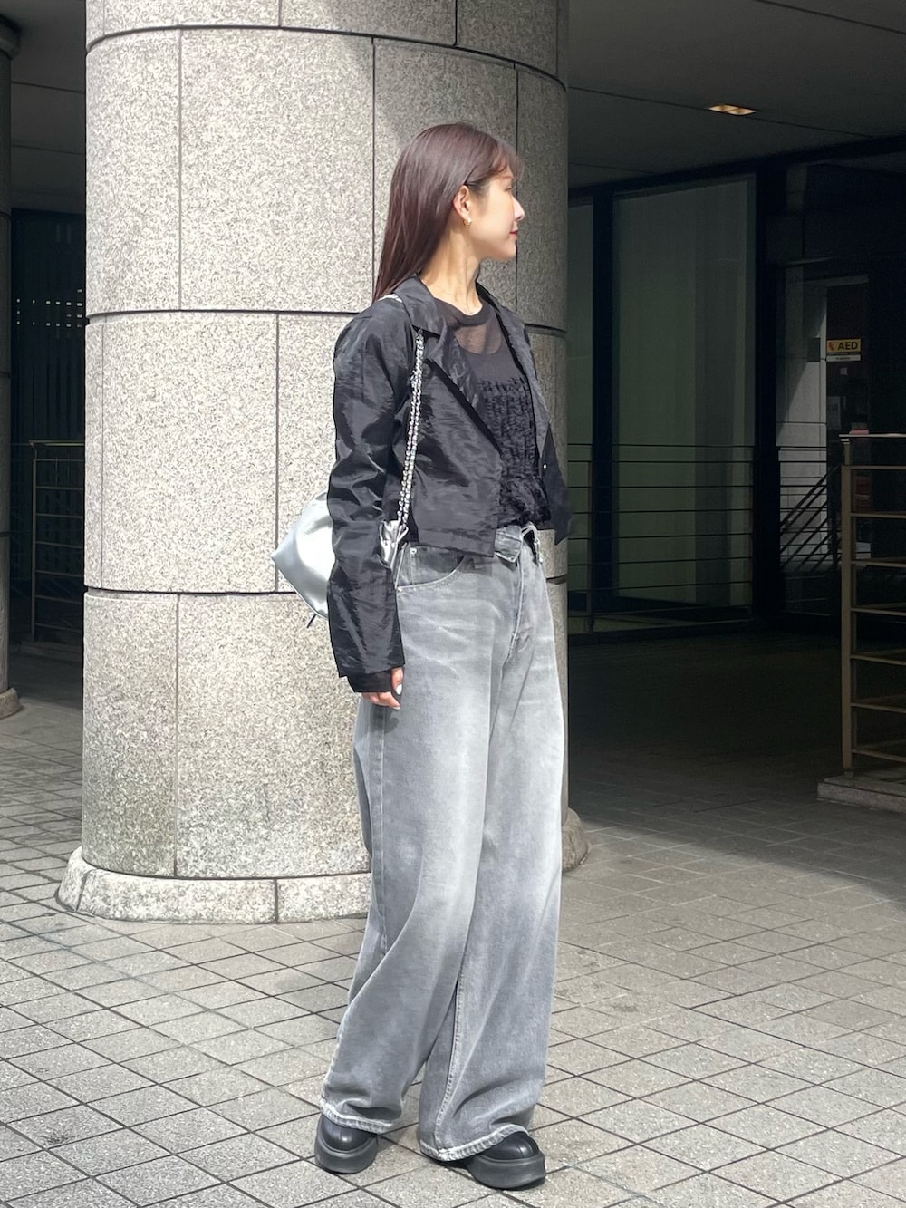 ブラック系のキャミソール、ブラック系のテーラードジャケット、ブラック系のデニムパンツを着用したレディースの春コーディネートの2枚目の写真