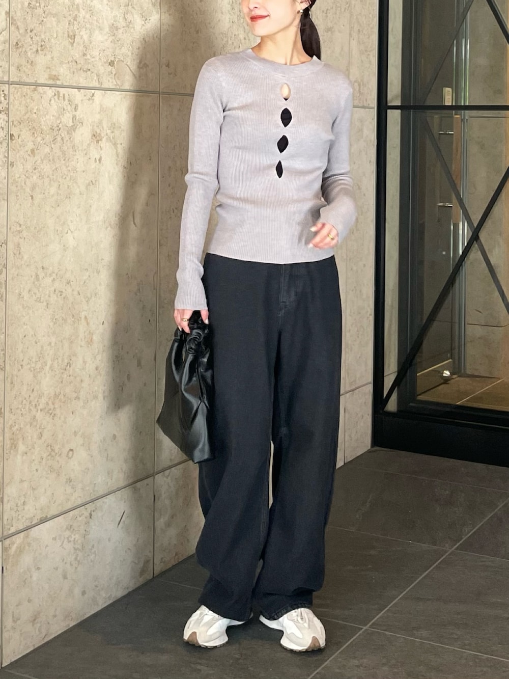 グレー系のニット/セーター、ブラック系のデニムパンツ、ホワイト系のスニーカーを着用したレディースの冬コーディネートの2枚目の写真