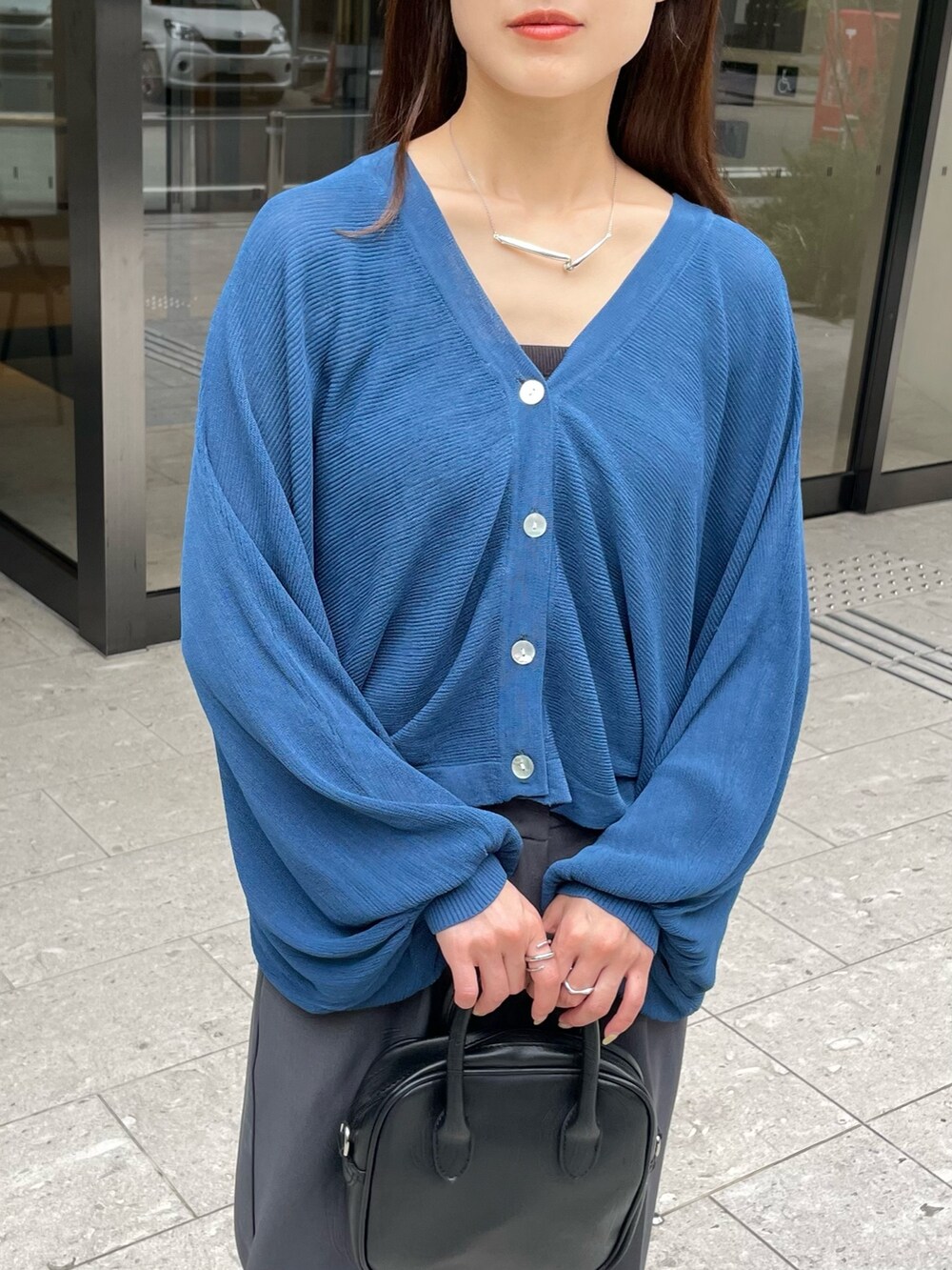 ブルー系のカーディガン/ボレロ、シルバー系のネックレスを着用したレディースの夏コーディネートの2枚目の写真