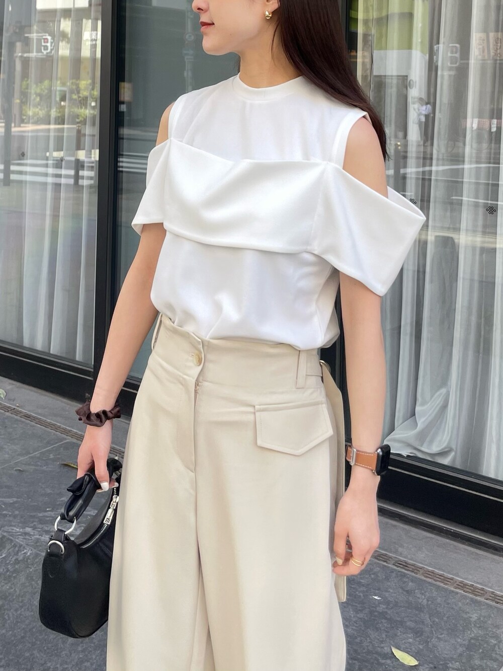 ホワイト系のTシャツ/カットソー、ブラック系のショルダーバッグ、ベージュ系のスラックスを着用したレディースの春コーディネートの3枚目の写真