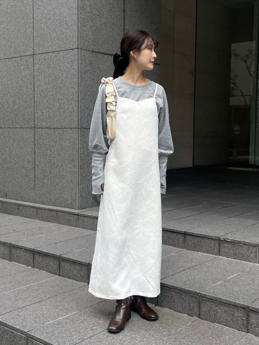 ホワイト系のワンピース、グレー系のTシャツ/カットソーを着用したレディースの春コーディネートの2枚目の写真