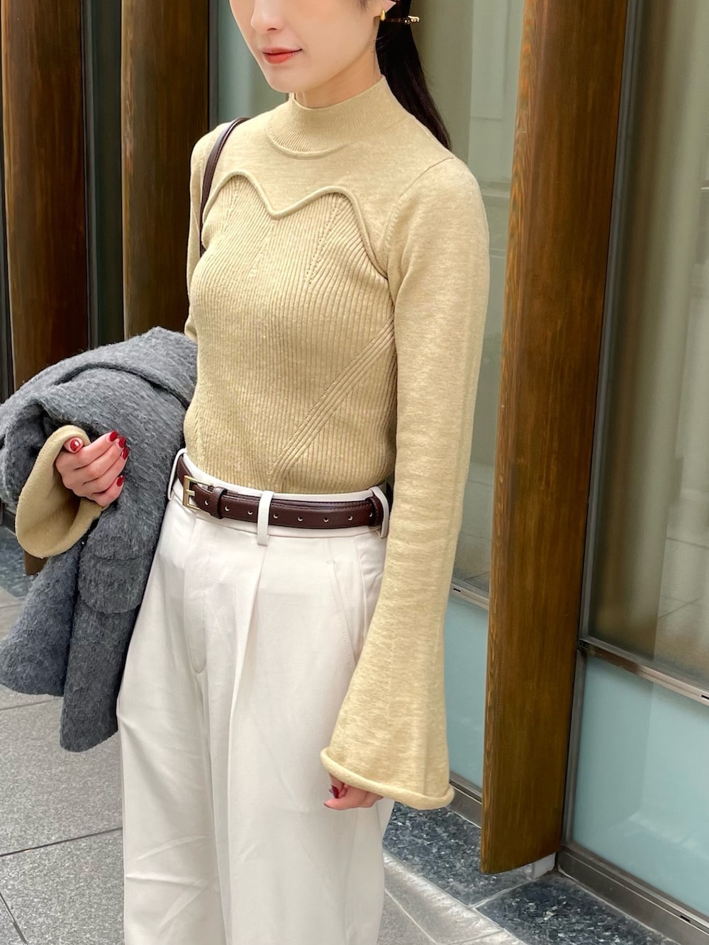 ベージュ系のニット/セーター、ホワイト系のパンツ、ブラウン系のブーツを着用したレディースの春コーディネートの3枚目の写真