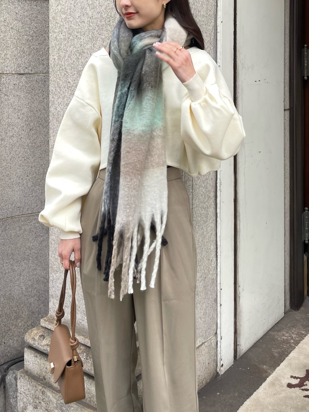 ブラウン系のブーツ、ブラウン系のハンドバッグ、ホワイト系のニット/セーターを着用したレディースの冬コーディネートの3枚目の写真