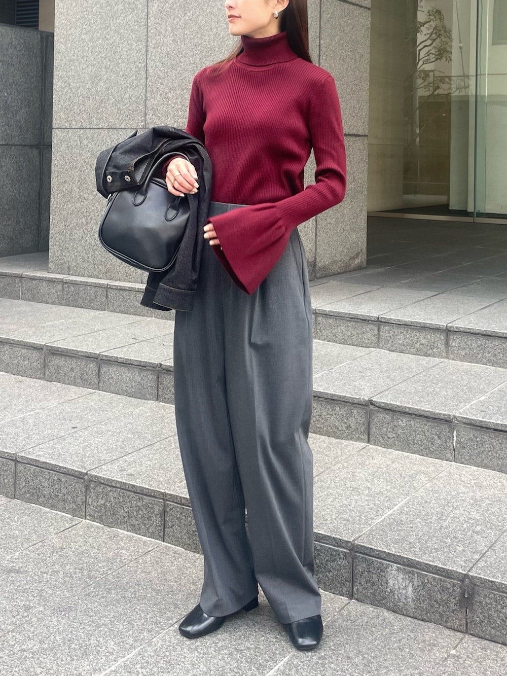 レッド系のニット/セーター、グレー系のパンツ、ブラック系のデニムジャケットを着用したレディースの秋コーディネートの2枚目の写真