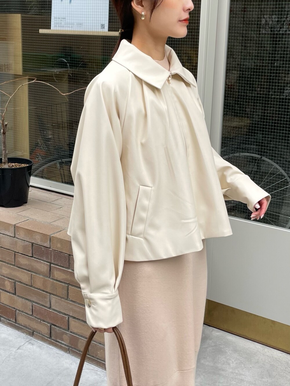 ホワイト系のブルゾン、ホワイト系のワンピース、ブラウン系のハンドバッグを着用したレディースの冬コーディネートの3枚目の写真