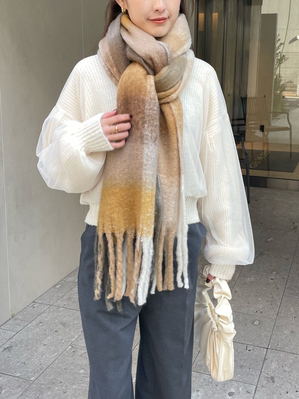 グレー系のパンツ、ホワイト系のニット/セーター、ゴールド系のバレッタ/ヘアクリップを着用したレディースの冬コーディネートの4枚目の写真