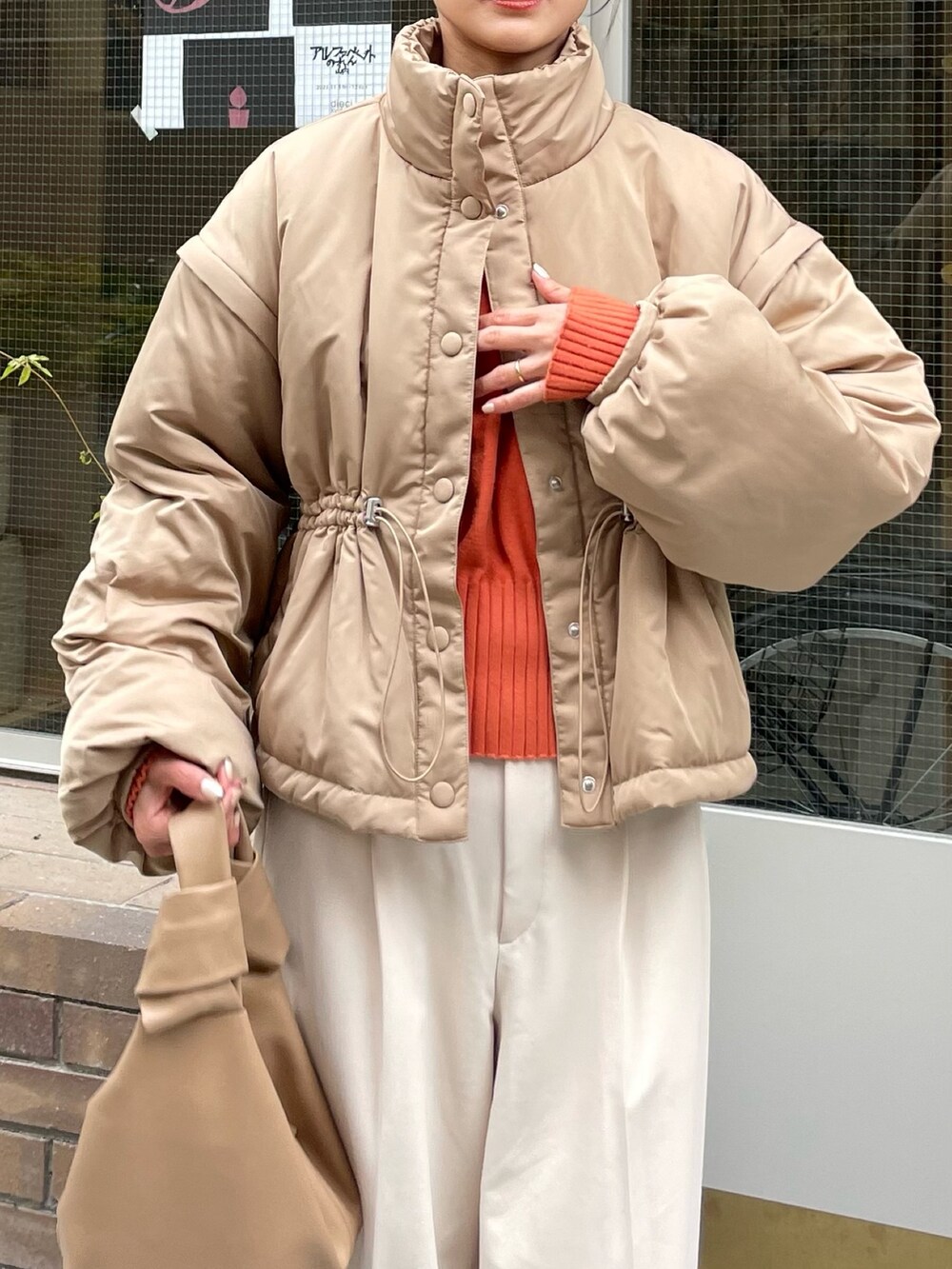 ベージュ系のダウンジャケット/コート、ホワイト系のパンツ、ブラウン系のブーツを着用したレディースの秋コーディネートの2枚目の写真