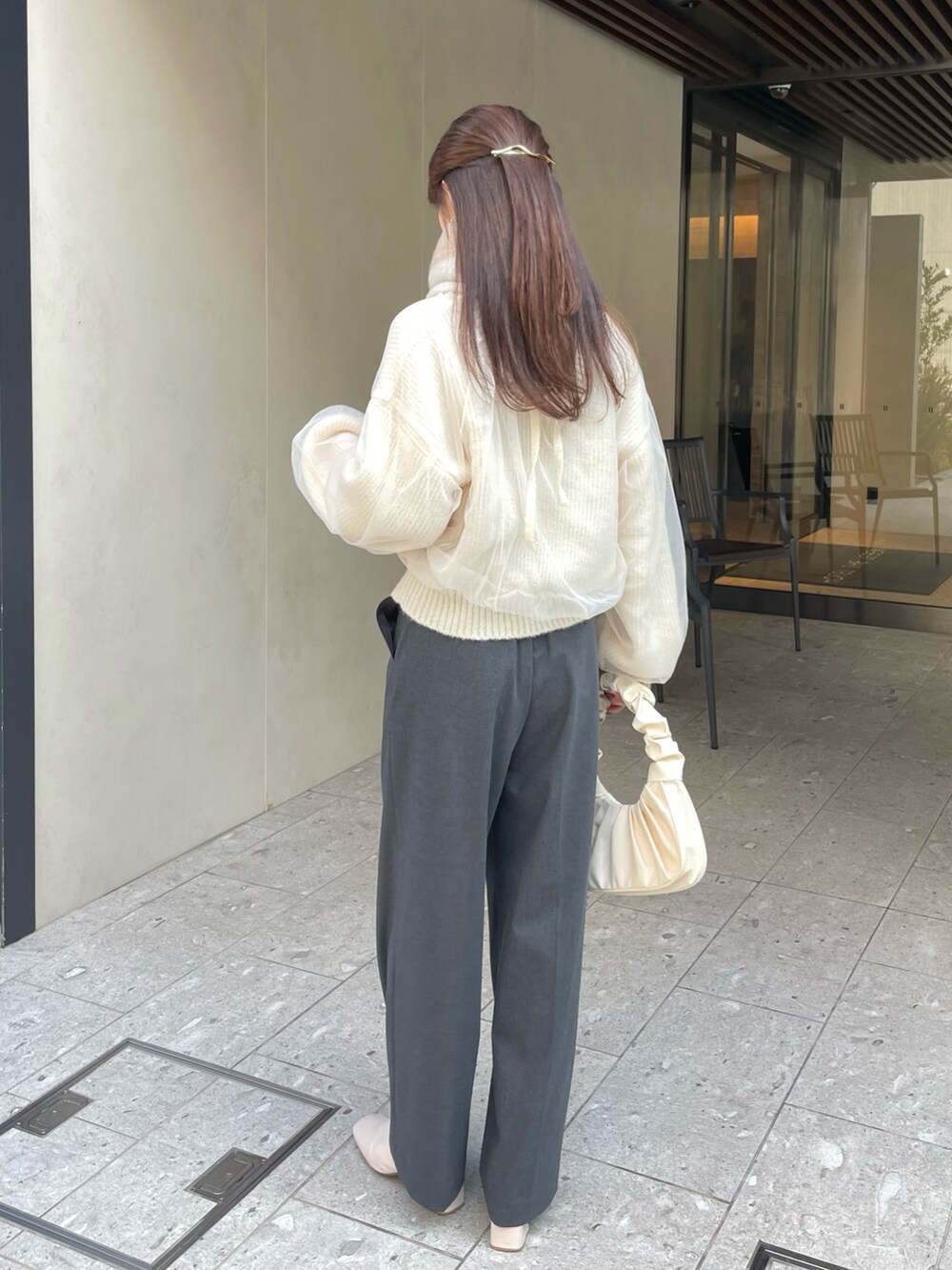 グレー系のパンツ、ホワイト系のニット/セーター、ゴールド系のバレッタ/ヘアクリップを着用したレディースの冬コーディネートの3枚目の写真