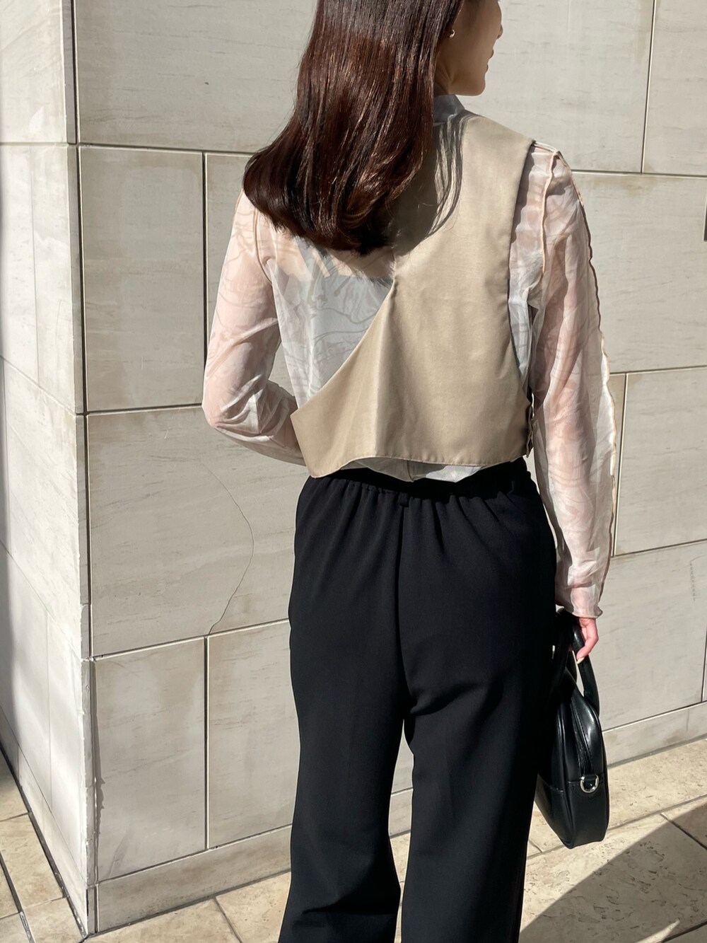 ブラック系のスラックス、ホワイト系のTシャツ/カットソー、ベージュ系のベストを着用したレディースの春コーディネートの2枚目の写真