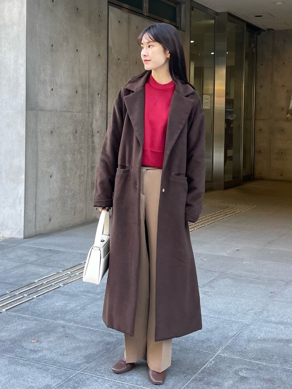 レッド系のニット/セーター、ブラウン系のブーツ、ベージュ系のパンツを着用したレディースの冬コーディネートの2枚目の写真