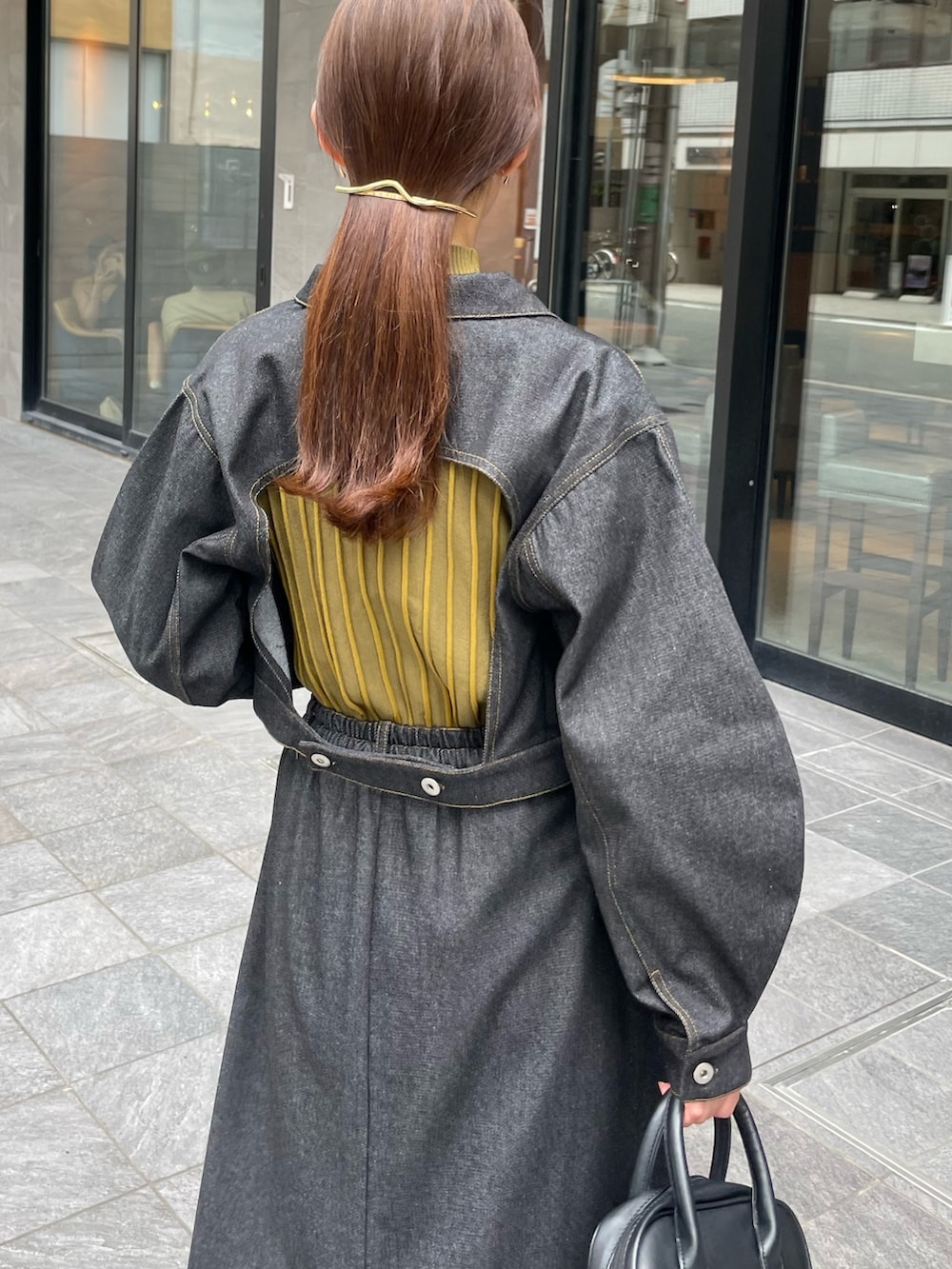 イエロー系のニット/セーター、ブラック系のスカート、ブラック系のデニムジャケットを着用したレディースの秋コーディネートの3枚目の写真