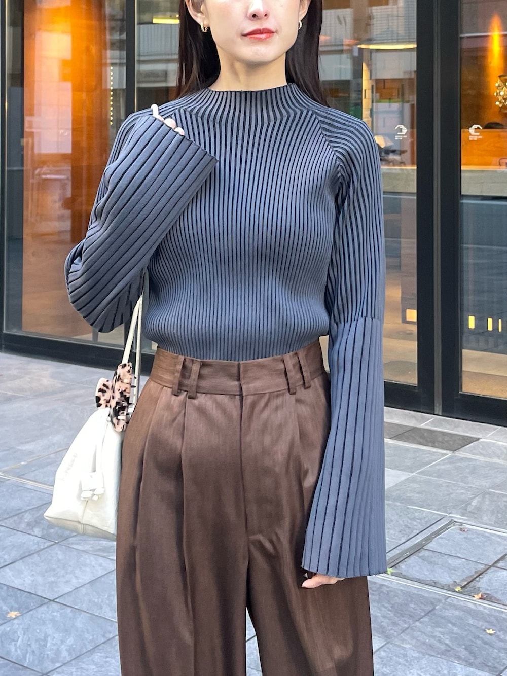 ブラウン系のスラックス、グレー系のニット/セーターを着用したレディースの冬コーディネートの2枚目の写真