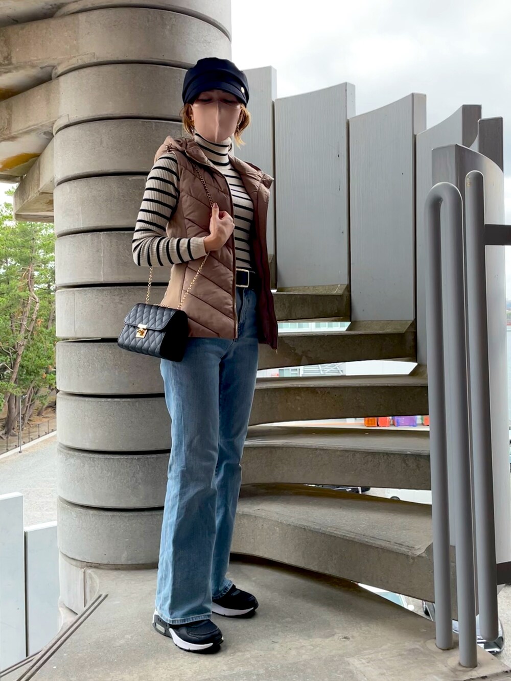 ベージュ系のダウンベスト、ホワイト系のニット/セーター、ブラック系のショルダーバッグを着用したレディースの秋コーディネートの2枚目の写真