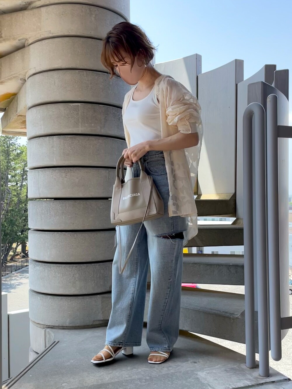 ホワイト系のタンクトップ、ブルー系のデニムパンツ、ベージュ系のショルダーバッグを着用したレディースの春コーディネートの2枚目の写真