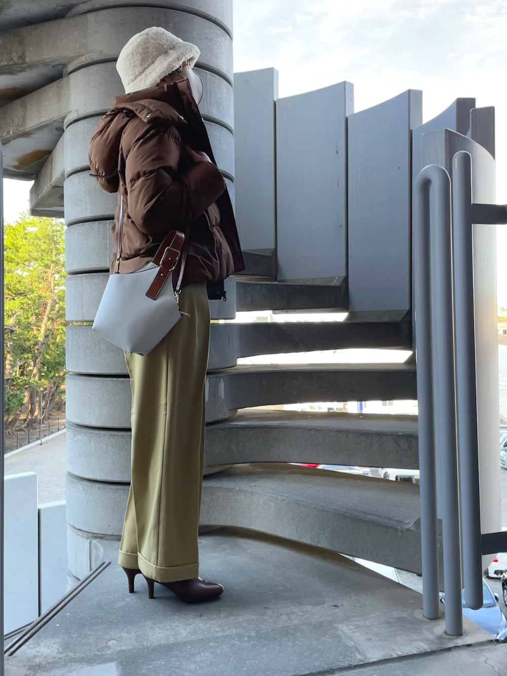 ブラウン系のダウンジャケット/コート、ホワイト系のニット/セーター、イエロー系のスラックスを着用したレディースの冬コーディネートの2枚目の写真