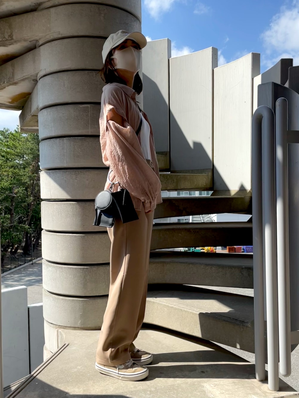 ピンク系のシャツ/ブラウス、ブラック系のショルダーバッグ、ベージュ系のスラックスを着用したレディースの秋コーディネートの3枚目の写真