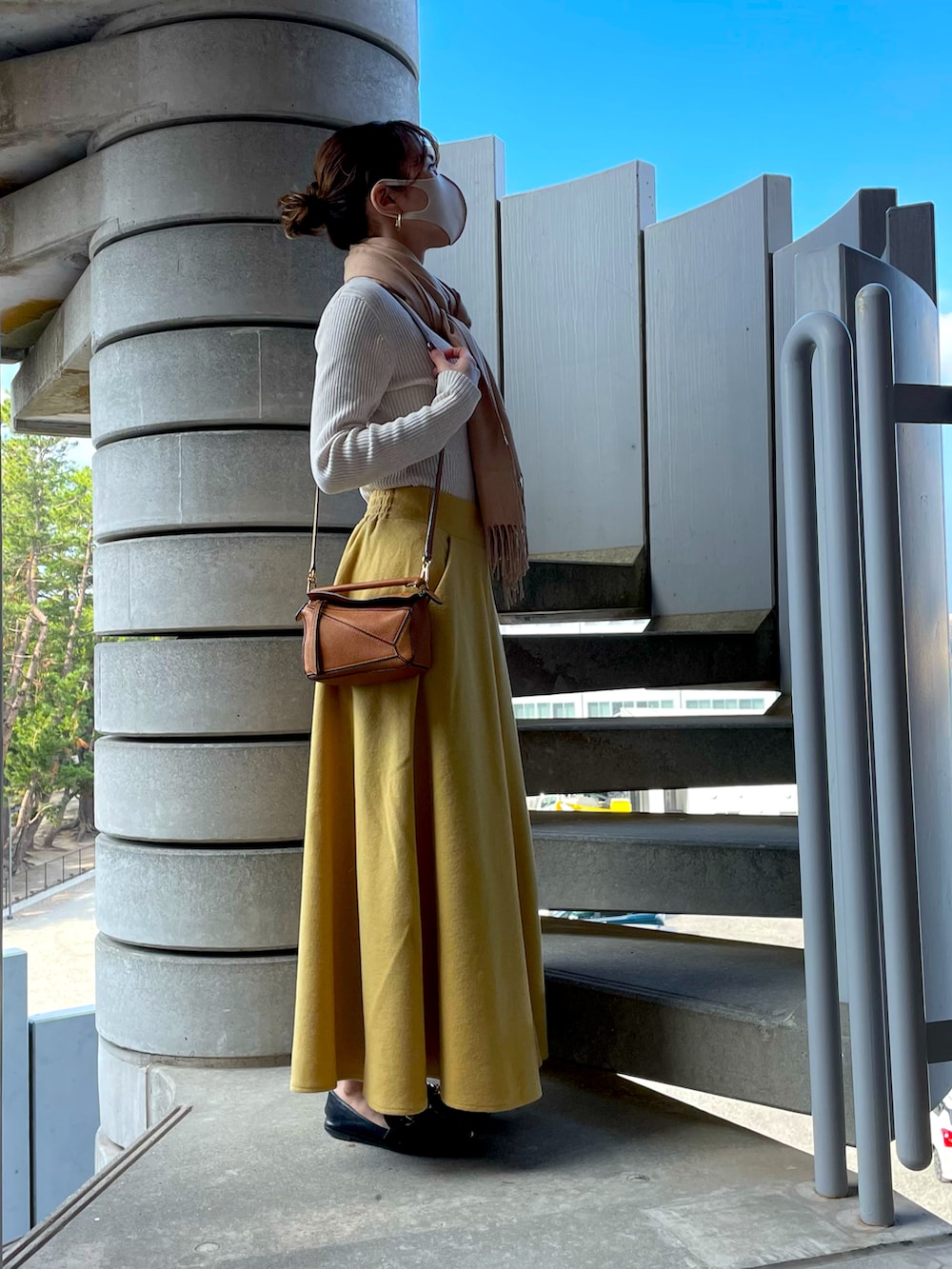 ブラック系のローファー、イエロー系のスカート、ベージュ系のハンドバッグを着用したレディースの秋コーディネートの2枚目の写真