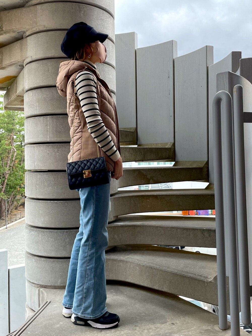 ベージュ系のダウンベスト、ホワイト系のニット/セーター、ブラック系のショルダーバッグを着用したレディースの秋コーディネートの3枚目の写真