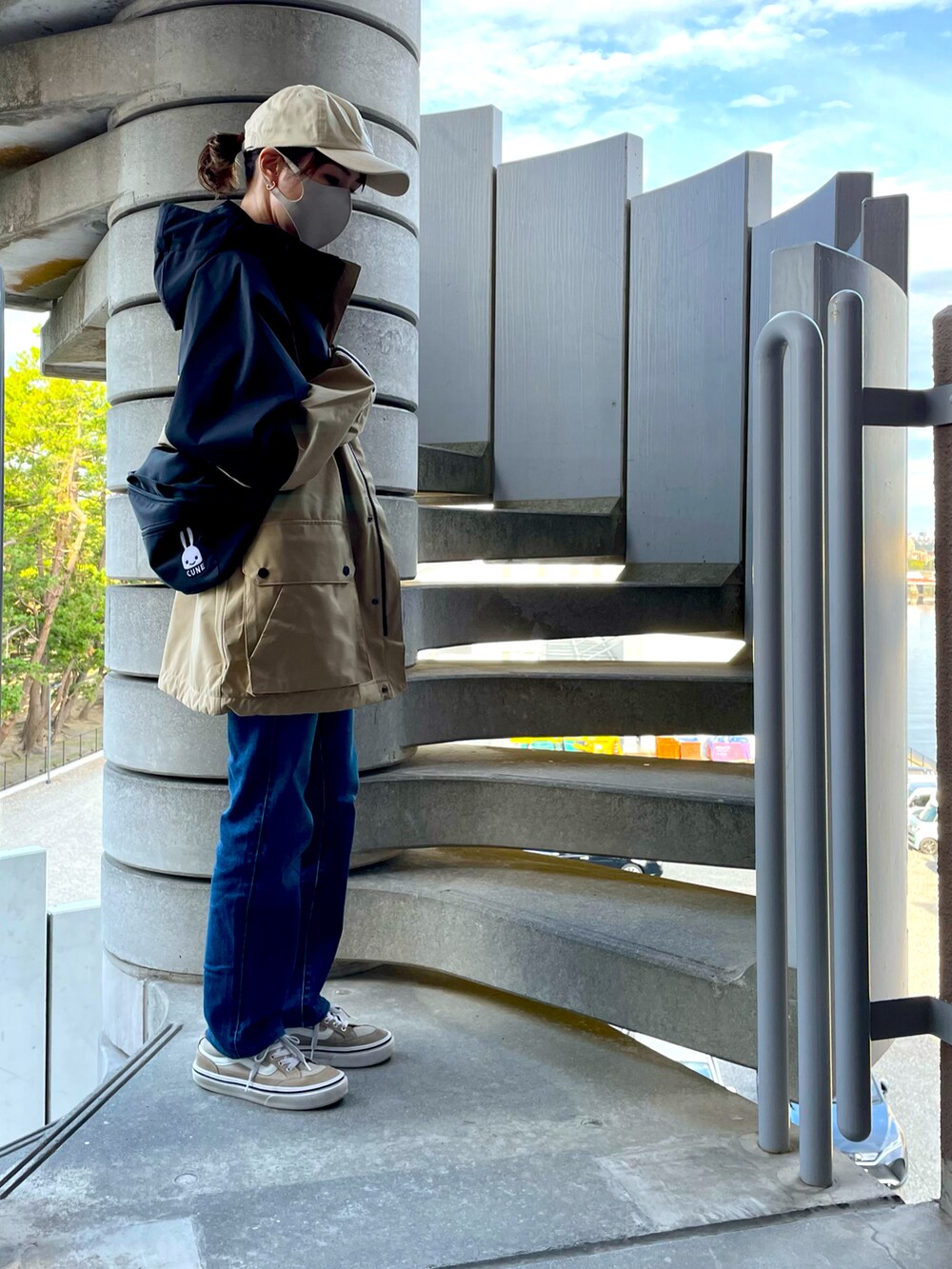 ベージュ系のマウンテンパーカー、ブラック系のボディバッグ/ウエストポーチ、ブルー系のデニムパンツを着用したレディースの秋コーディネートの2枚目の写真