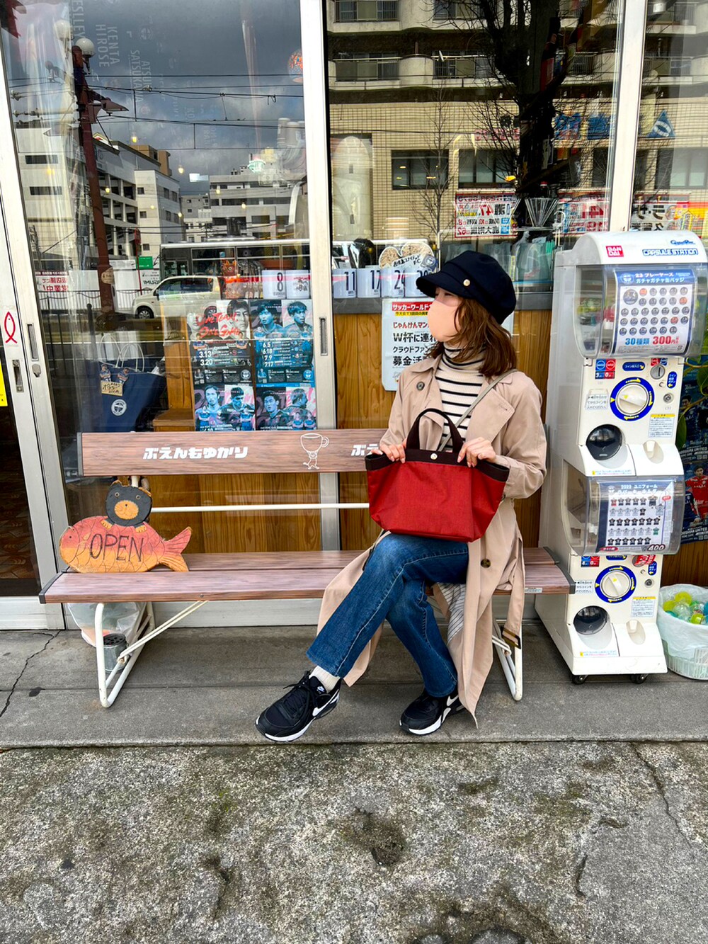 レッド系のハンドバッグ、ブルー系のデニムパンツ、ブラック系のスニーカーを着用したレディースの春コーディネートの3枚目の写真