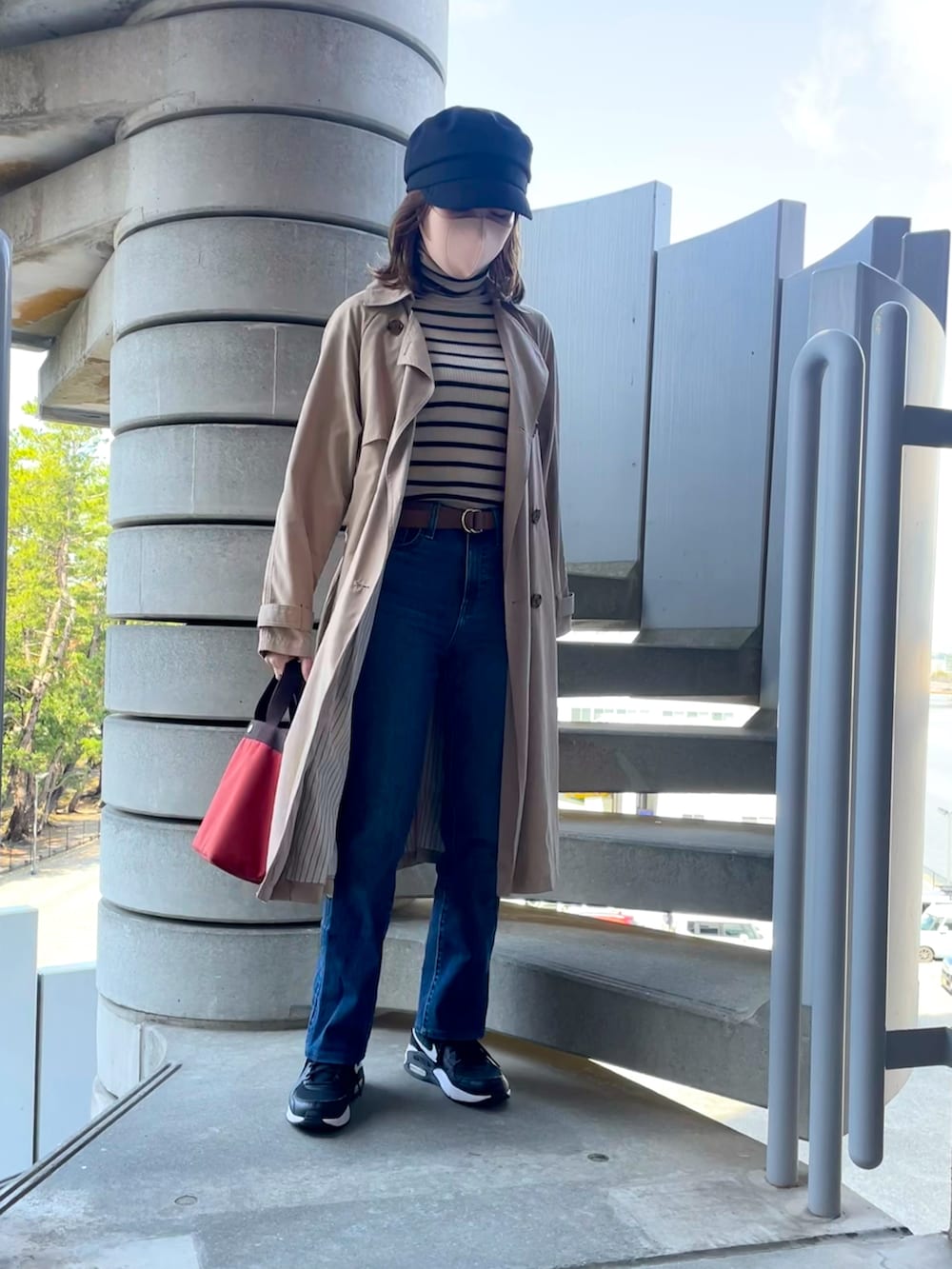 レッド系のハンドバッグ、ブルー系のデニムパンツ、ブラック系のスニーカーを着用したレディースの春コーディネートの2枚目の写真