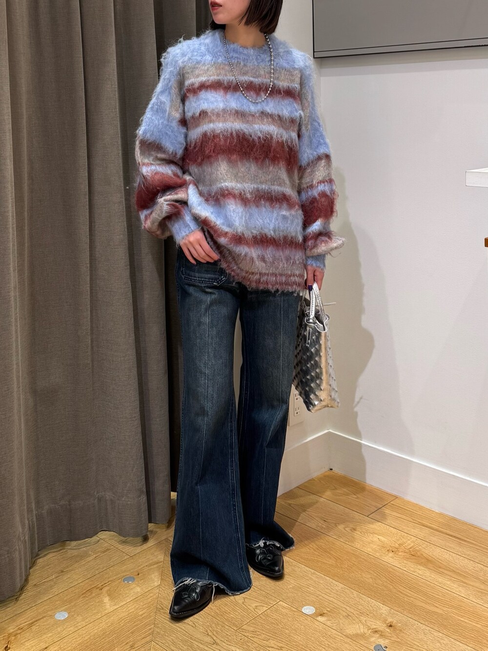 ブルー系のニット/セーター、ブルー系のデニムパンツ、ブラック系のブーツを着用したレディースの冬コーディネートの5枚目の写真