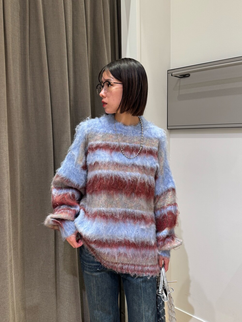 ブルー系のニット/セーター、ブルー系のデニムパンツ、ブラック系のブーツを着用したレディースの冬コーディネートの4枚目の写真