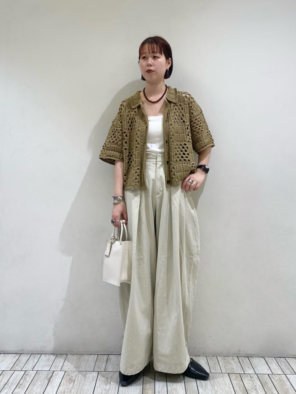 グリーン系のニット/セーター、ホワイト系のハンドバッグ、ブラウン系のネックレスを着用したレディースの春コーディネートの3枚目の写真