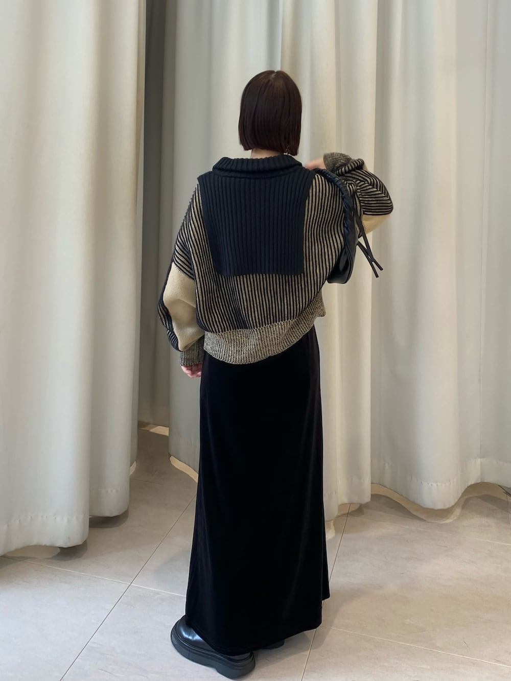 ブラック系のニット/セーター、ブラック系のスカート、ブラック系のハンドバッグを着用したレディースの秋コーディネートの4枚目の写真