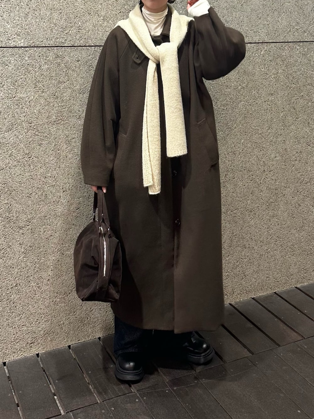 ブラウン系のステンカラーコート、ブラウン系のボストンバッグ、ブルー系のデニムパンツを着用したレディースの冬コーディネートの3枚目の写真