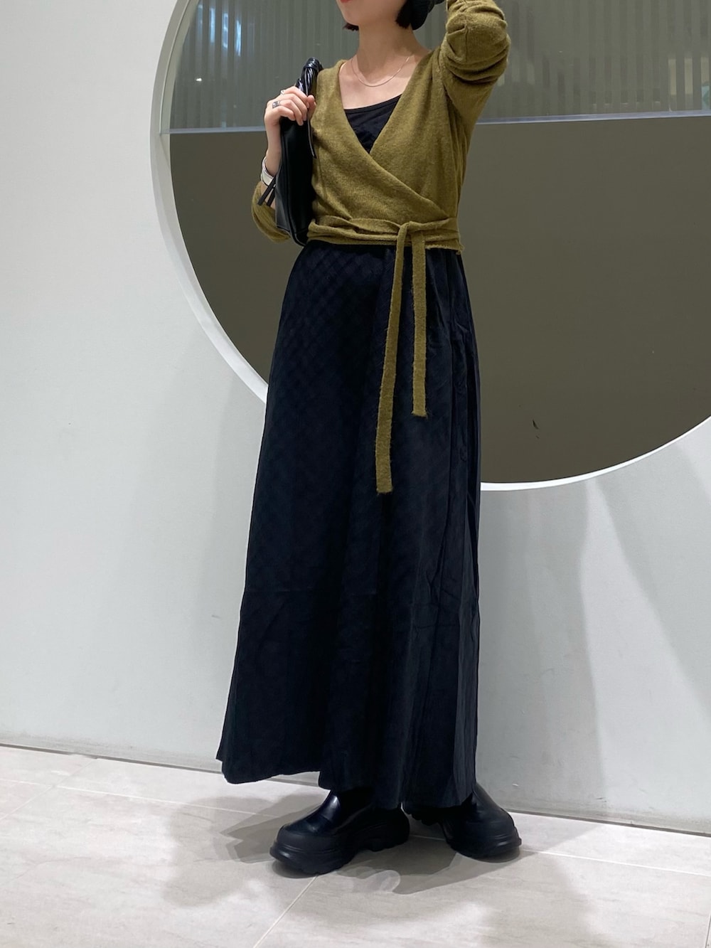 グリーン系のワンピース、ブラック系のブーツ、ブルー系のニット/セーターを着用したレディースの秋コーディネートの3枚目の写真