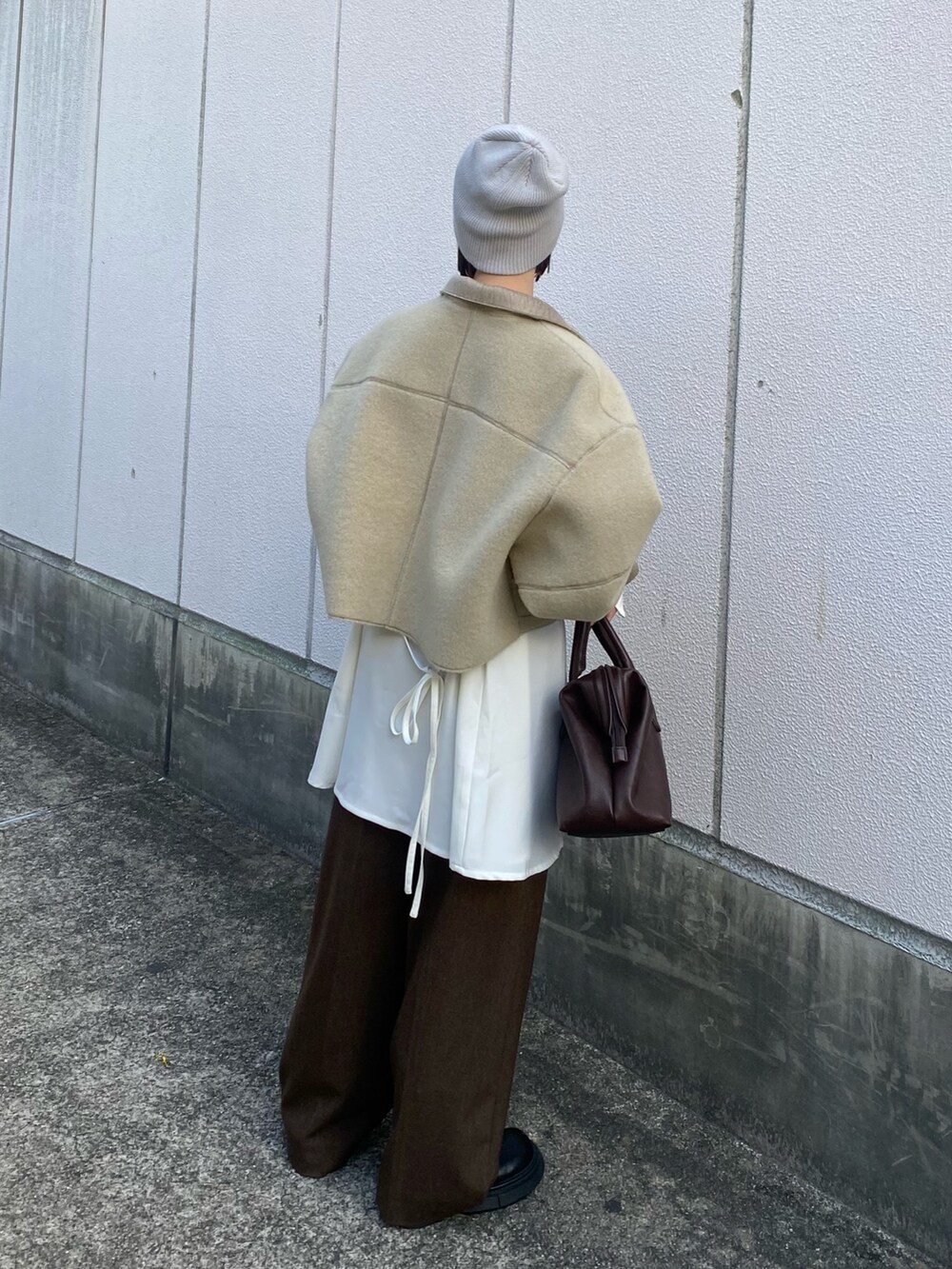 ベージュ系のその他アウター、ブラウン系のボストンバッグ、ホワイト系のワンピースを着用したレディースの秋コーディネートの5枚目の写真