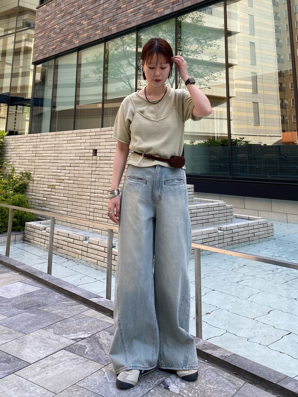 ブルー系のデニムパンツ、ベージュ系のカーディガン/ボレロ、ブラウン系のベルトを着用したレディースの春コーディネートの2枚目の写真