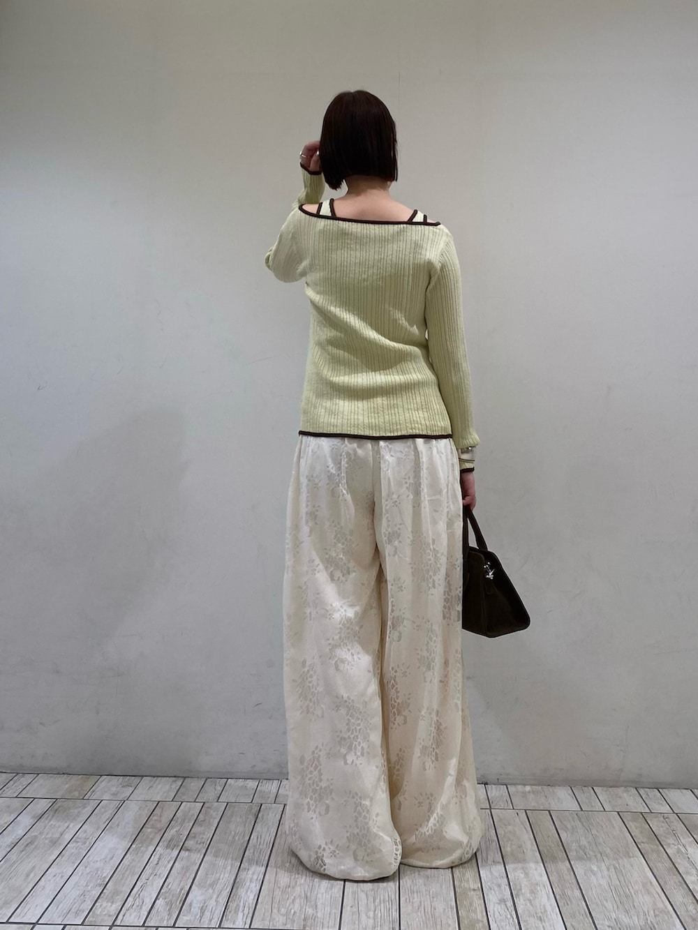 ホワイト系のその他パンツ、グリーン系のニット/セーター、ブラウン系のボストンバッグを着用したレディースの春コーディネートの4枚目の写真