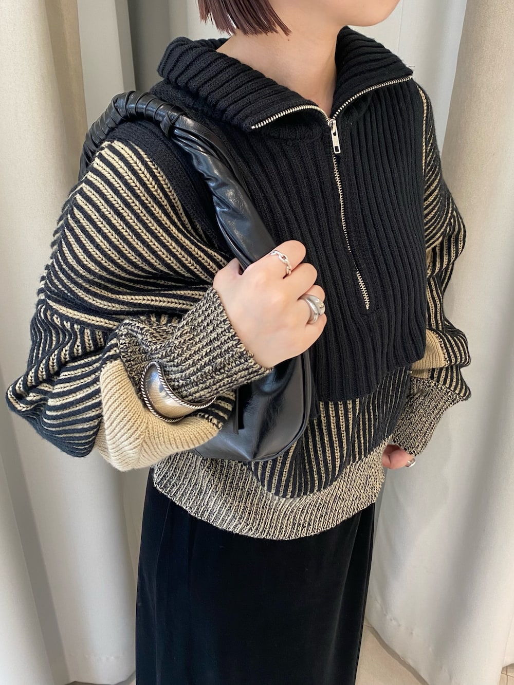 ブラック系のニット/セーター、ブラック系のスカート、ブラック系のハンドバッグを着用したレディースの秋コーディネートの3枚目の写真