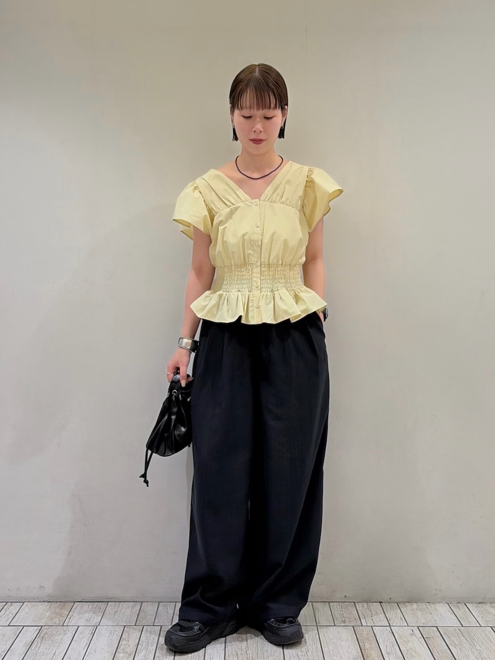 イエロー系のシャツ/ブラウス、ブルー系のその他パンツ、ブラック系のハンドバッグを着用したレディースの夏コーディネートの2枚目の写真