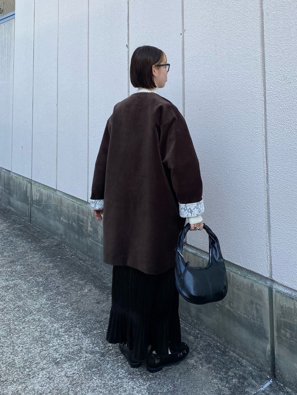 ブラック系のハンドバッグ、ブラウン系のワンピース、ブラック系のその他シューズを着用したレディースの冬コーディネートの4枚目の写真