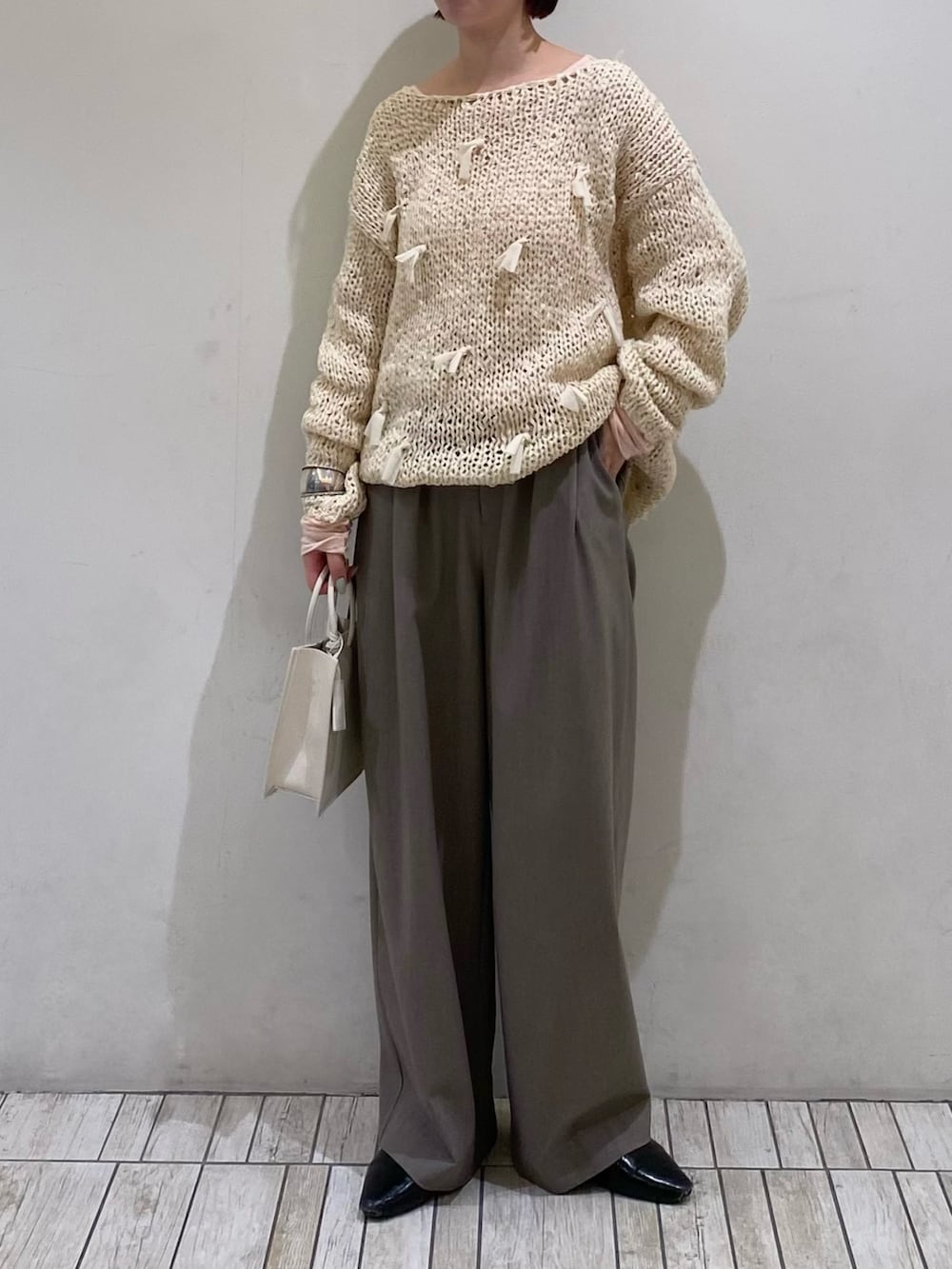 ホワイト系のニット/セーター、ホワイト系のハンドバッグ、グレー系のその他パンツを着用したレディースの春コーディネートの2枚目の写真