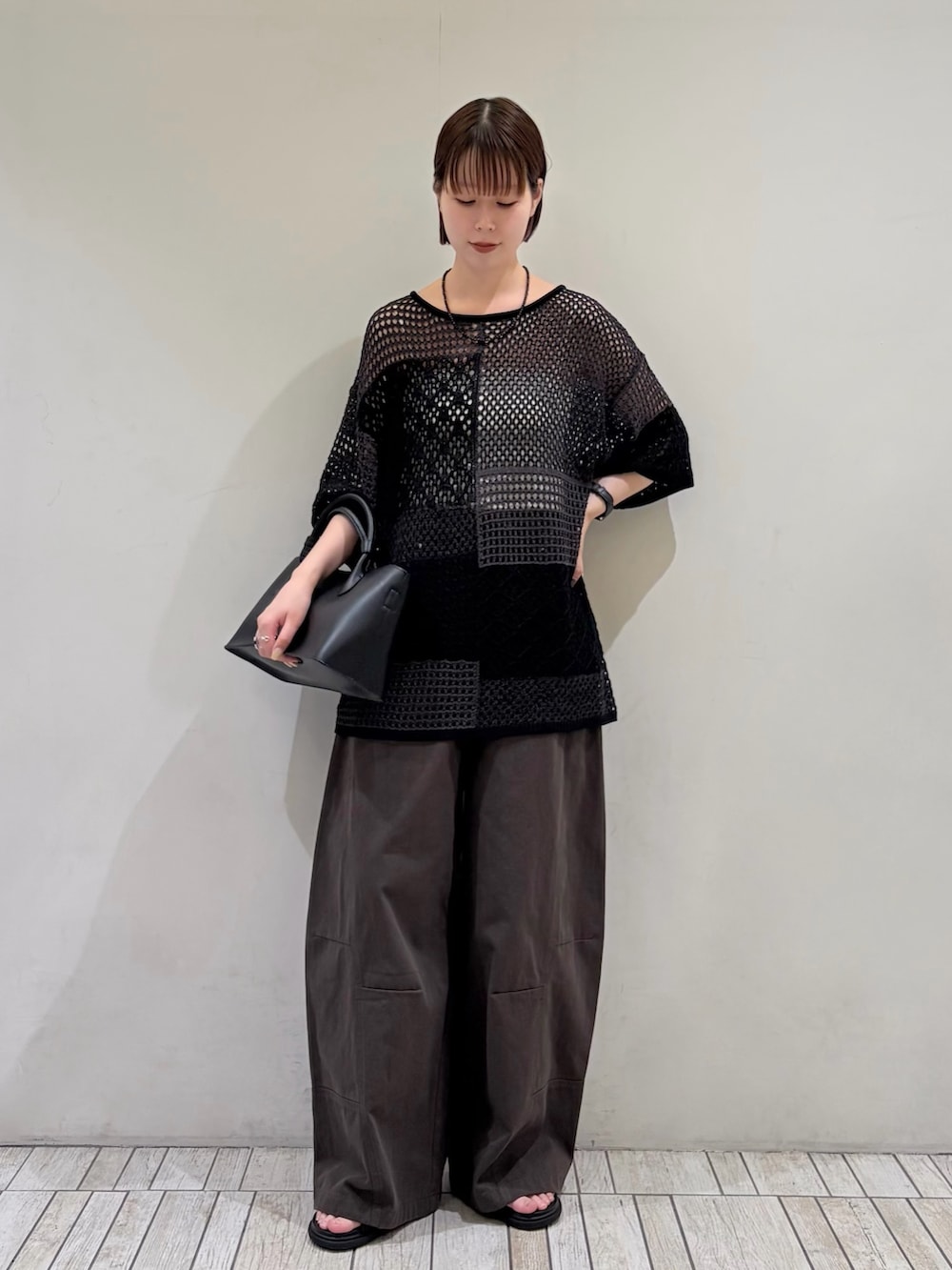 グレー系のその他パンツ、ブラック系のハンドバッグ、グレー系のニット/セーターを着用したレディースの夏コーディネートの2枚目の写真