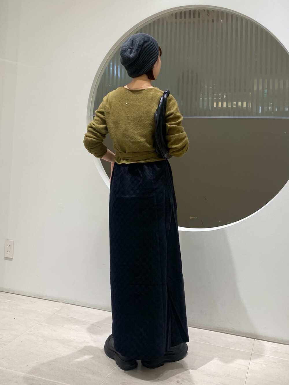 グリーン系のワンピース、ブラック系のブーツ、ブルー系のニット/セーターを着用したレディースの秋コーディネートの4枚目の写真