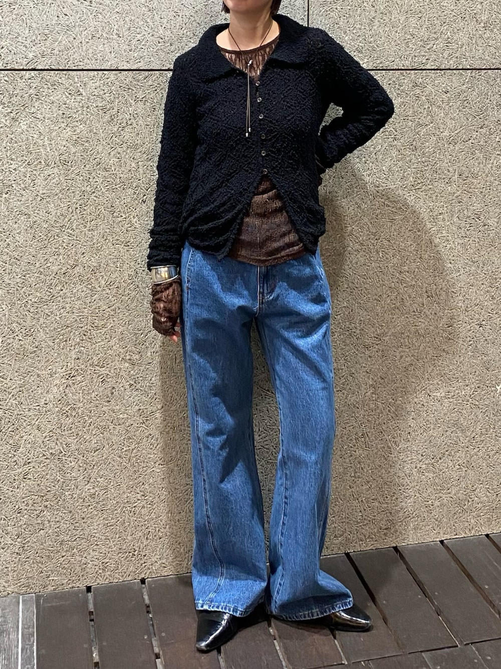 ブラック系のニット/セーター、ブラウン系のTシャツ/カットソー、ブルー系のデニムパンツを着用したレディースの冬コーディネートの2枚目の写真