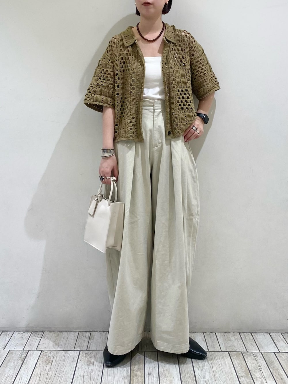 グリーン系のニット/セーター、ホワイト系のハンドバッグ、ブラウン系のネックレスを着用したレディースの春コーディネートの2枚目の写真