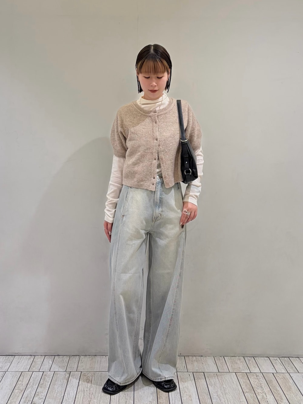 ベージュ系のカーディガン/ボレロ、ブルー系のデニムパンツ、ブラック系のショルダーバッグを着用したレディースの秋コーディネートの2枚目の写真